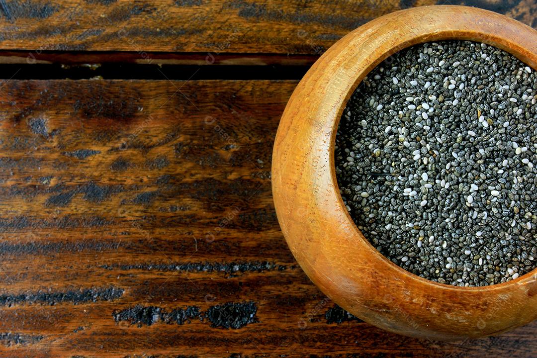 Sementes de chia de close-up em tigela de madeira isoladas na mesa rústica