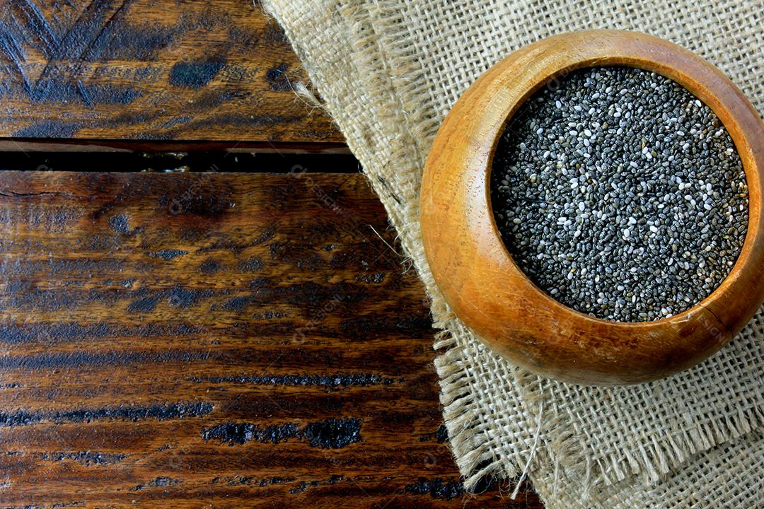Sementes de chia de em tigela de madeira isoladas na mesa rústica