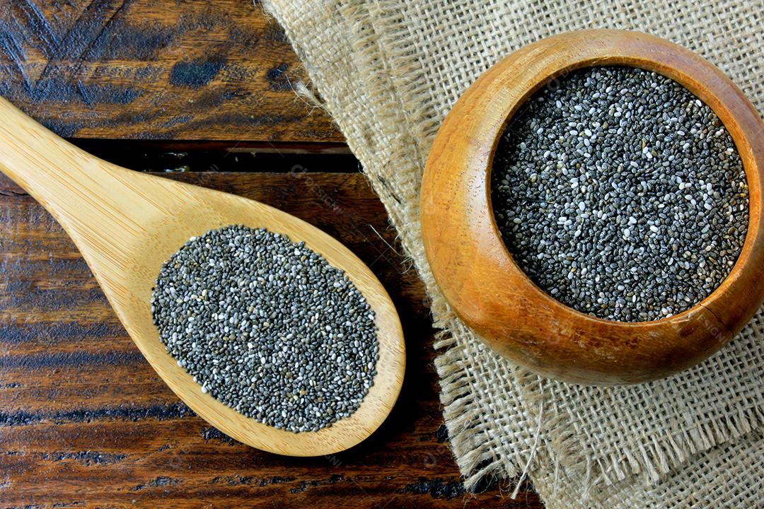 Sementes de chia de em tigela de madeira isoladas na mesa rústica