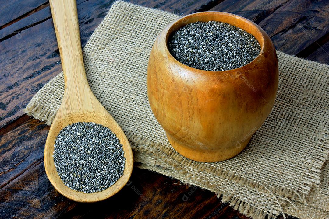 Sementes de chia de em tigela de madeira isoladas na mesa rústica