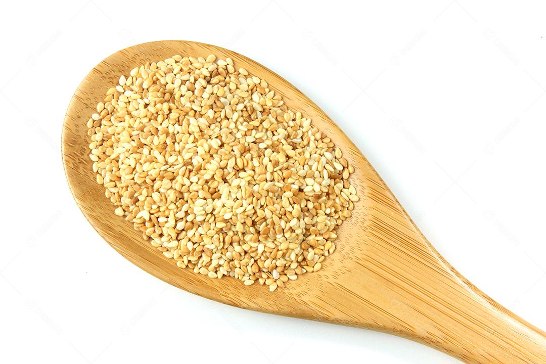 Sementes de gergelim em colher de pau, isoladas no fundo branco, vista superior. fotografia macro