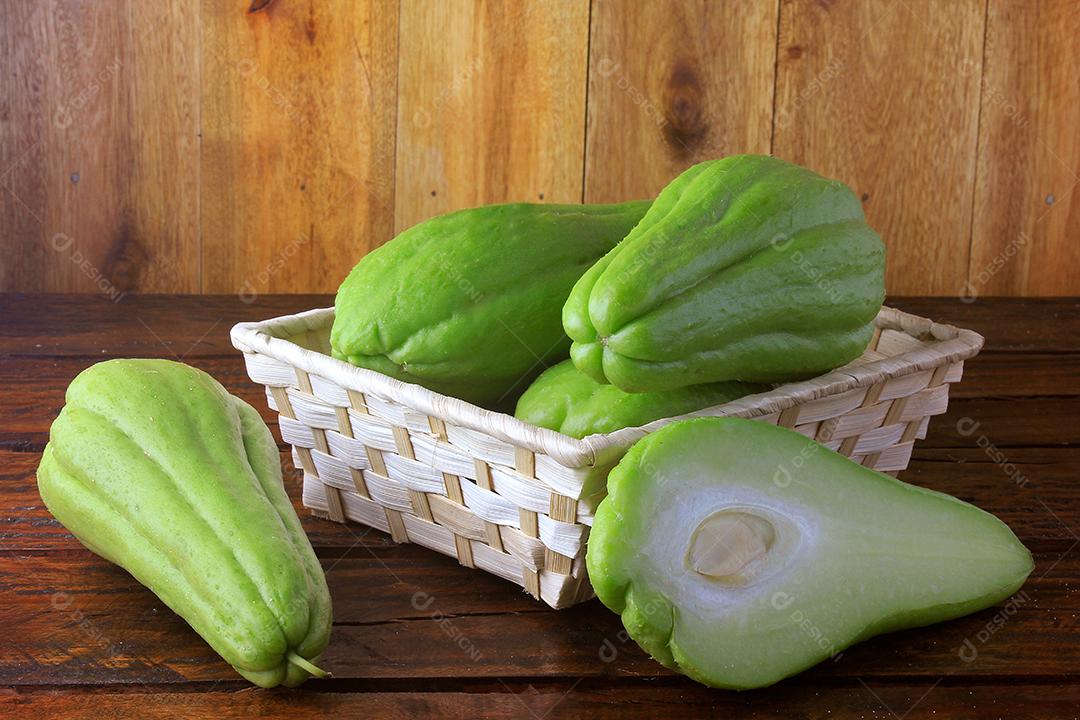 chuchu cru, fresco e orgânico, inteiro e fatiado na cesta na mesa de madeira rústica