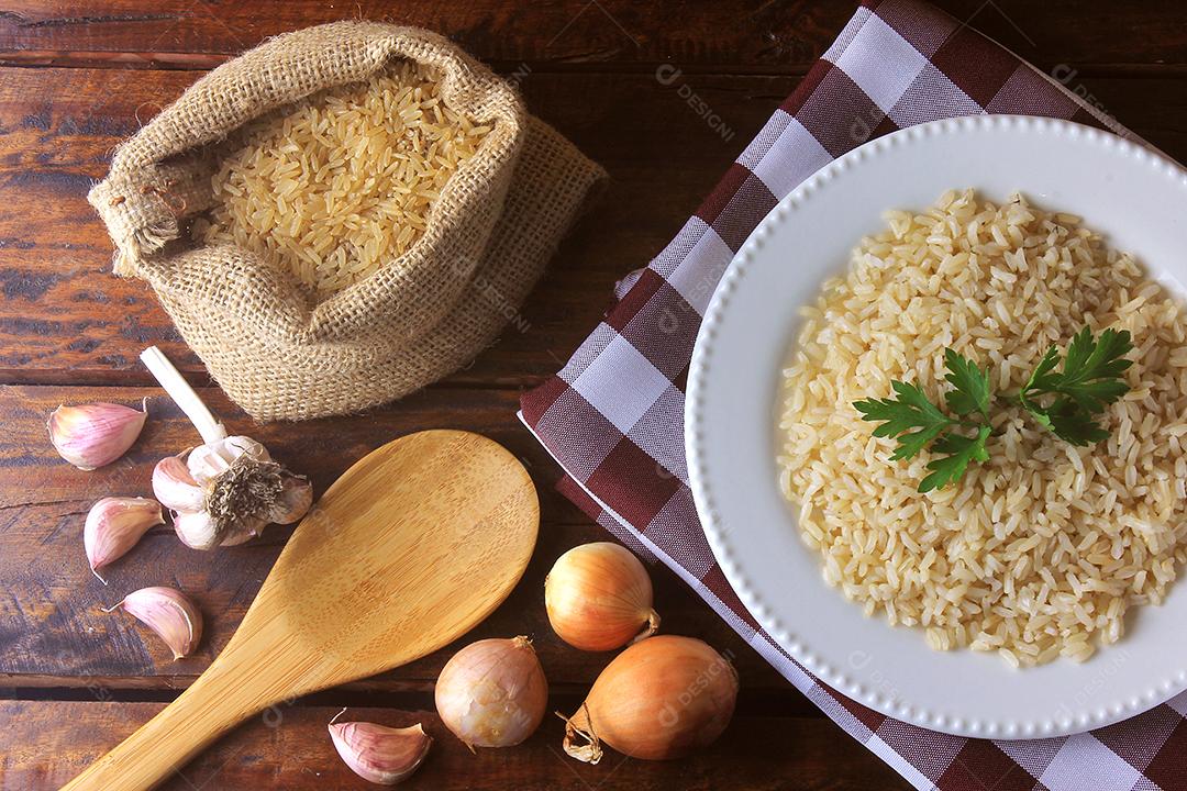 arroz integral no saco rústico ao lado do prato cerâmico e ingredientes para cozinhar na cozinha