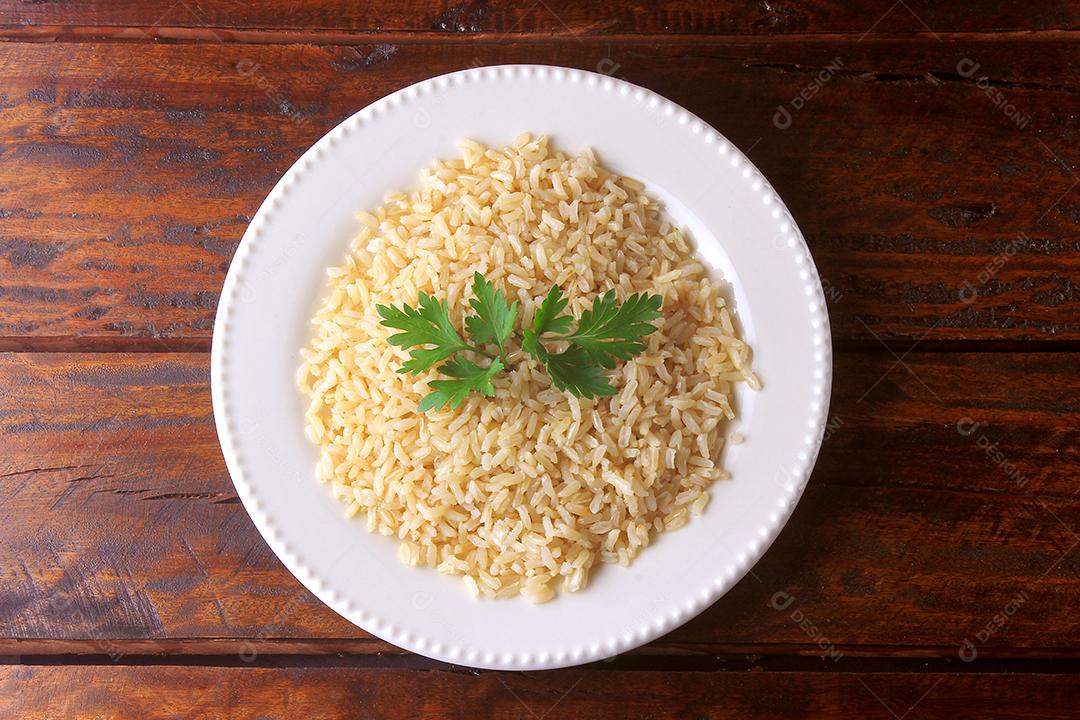 grão de arroz integral orgânico cozido em prato branco na mesa de madeira rústica. Arroz integral Vista superior
