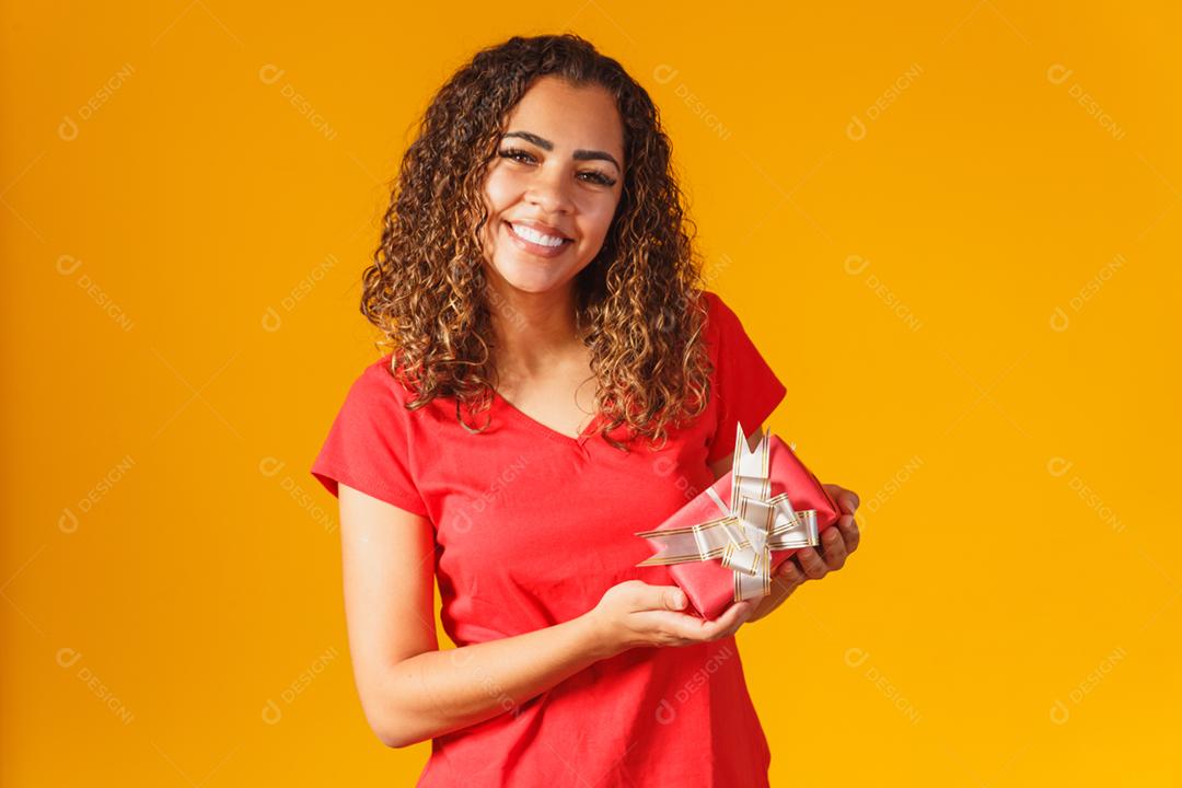 mulher afro segurando um presente na mão.