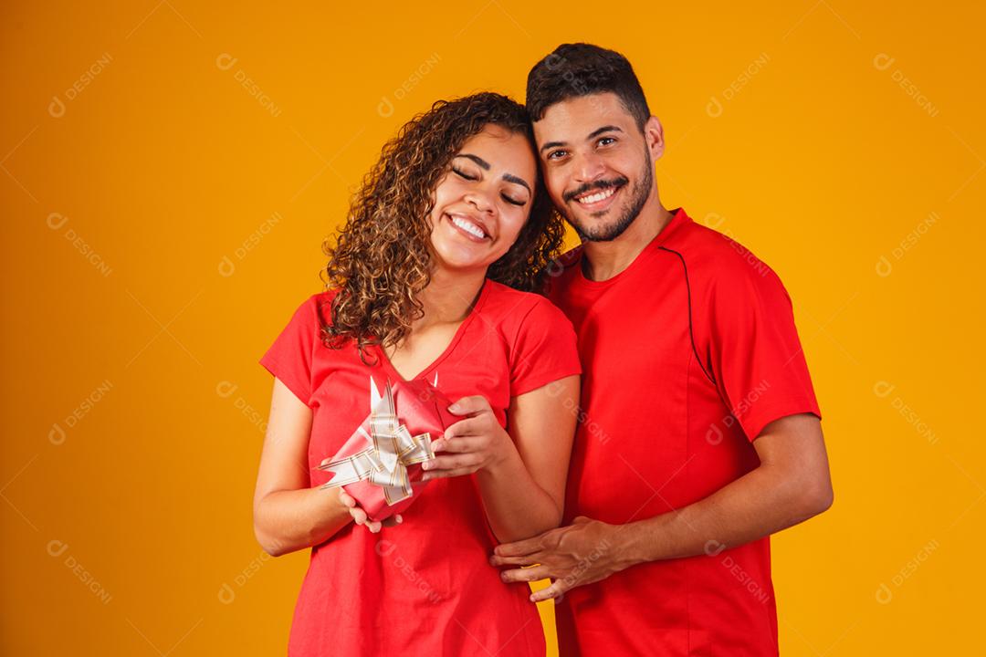 Retrato de um lindo casal em fundo amarelo com um presente