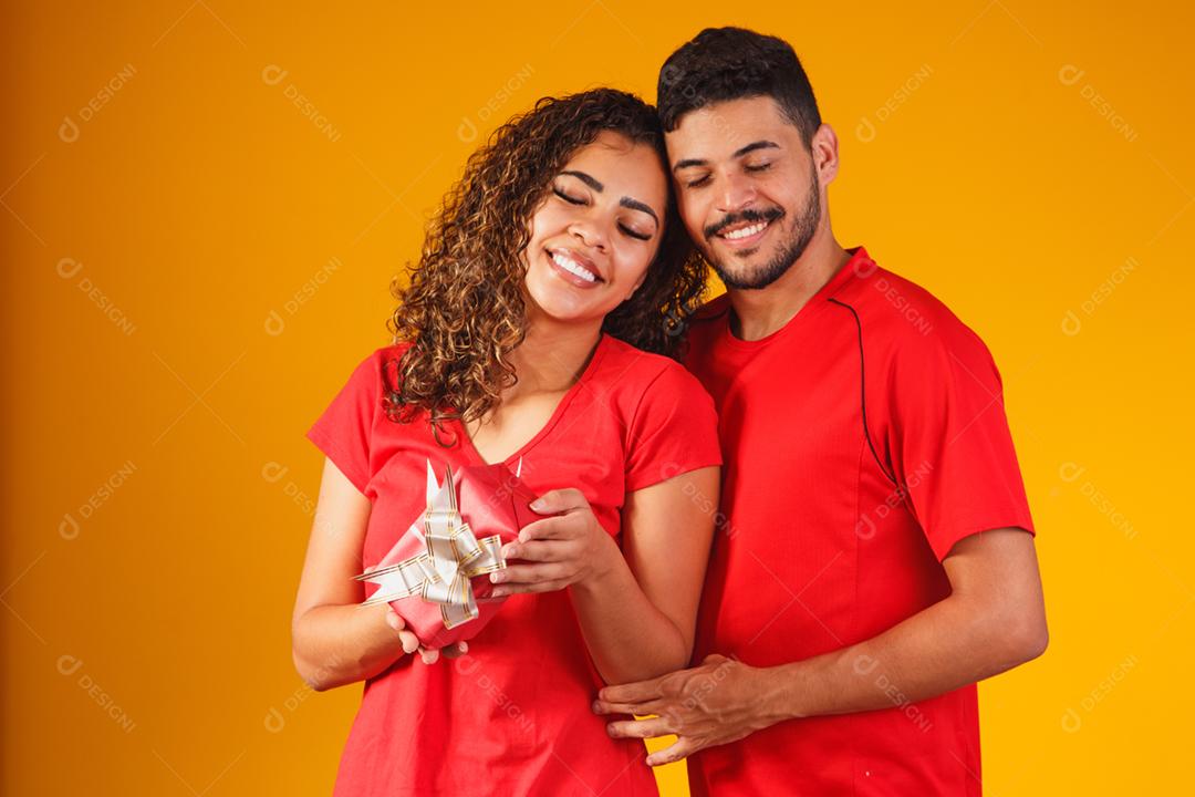 Retrato de um lindo casal em fundo amarelo com um presente