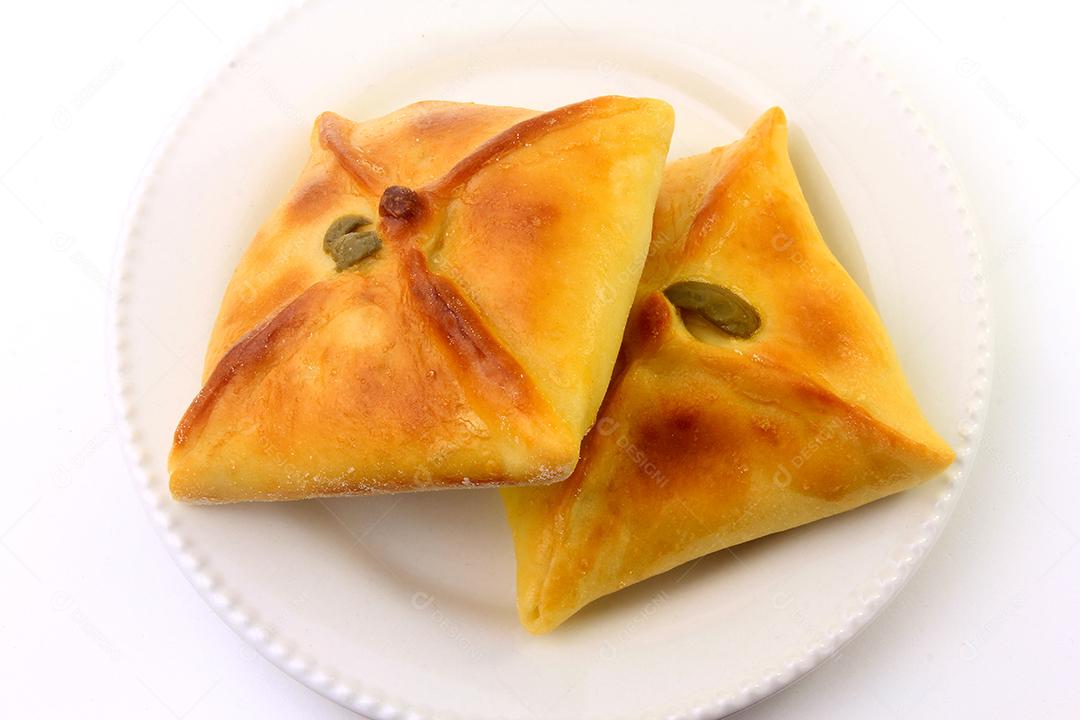 Esfiha de frango de origem árabe tradicionalmente adaptada para cozinha brasileira em prato fundo branco