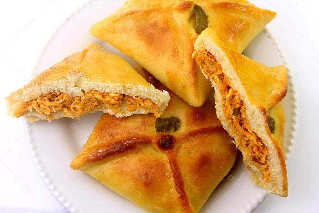 Esfiha de frango de origem árabe tradicionalmente adaptada para cozinha brasileira em prato fundo branco