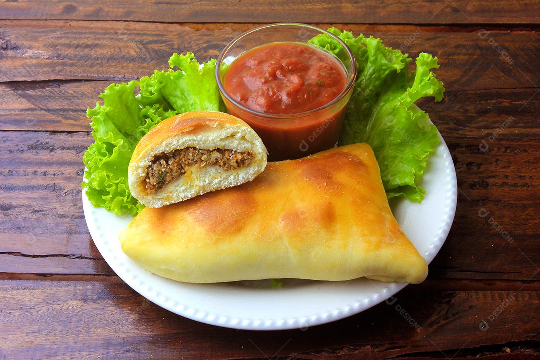 esfiha de carne (sfiha, sfeeha) de origem árabe tradicionalmente adaptada para a culinária brasileira no prato na mesa