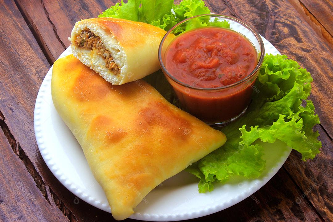 esfiha de carne (sfiha, sfeeha) de origem árabe tradicionalmente adaptada para a culinária brasileira no prato na mesa