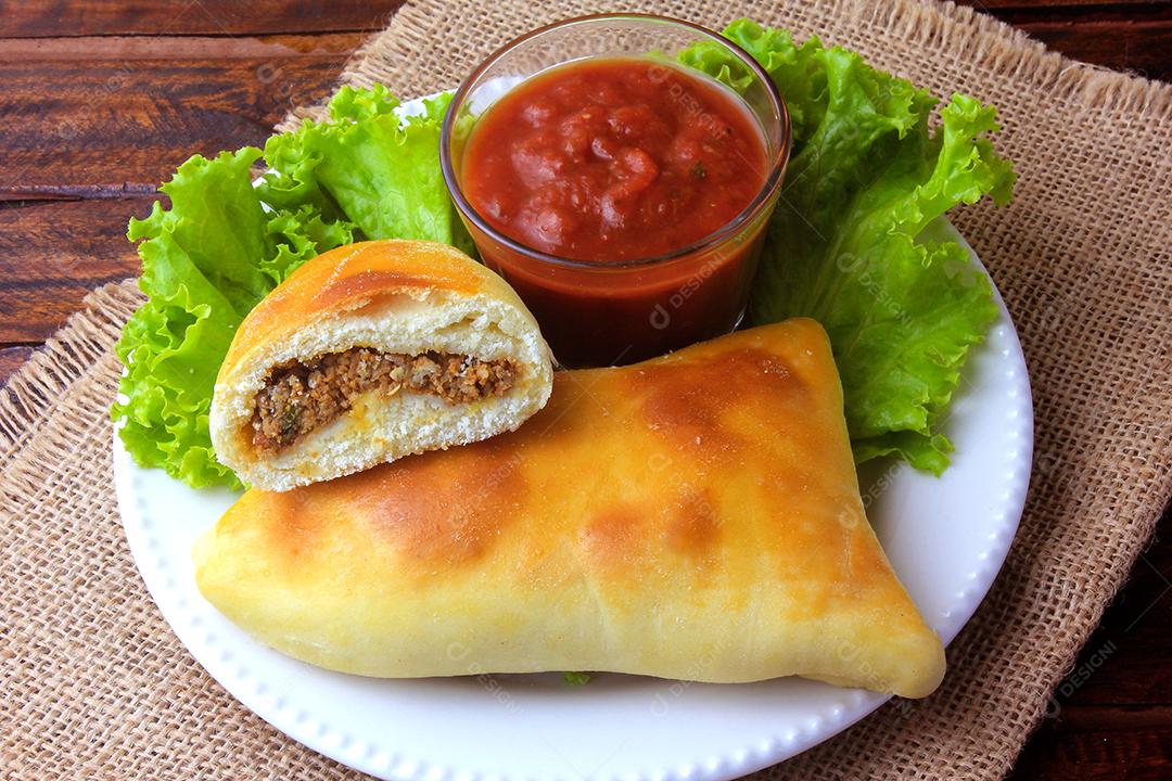 esfiha de carne (sfiha, sfeeha) de origem árabe tradicionalmente adaptada para a culinária brasileira no prato na mesa