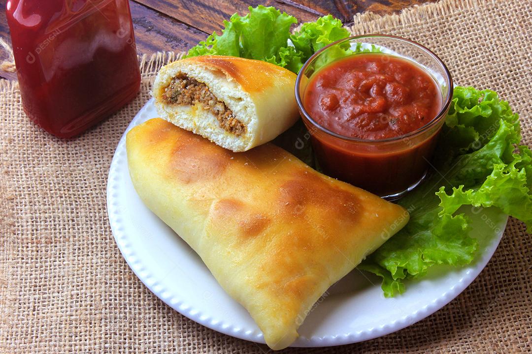 esfiha de carne (sfiha, sfeeha) de origem árabe tradicionalmente adaptada para a culinária brasileira no prato na mesa