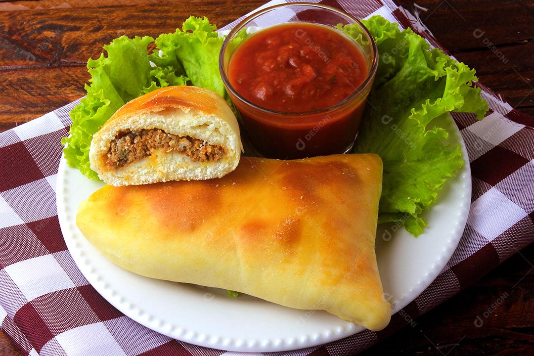 esfiha de carne (sfiha, sfeeha) de origem árabe tradicionalmente adaptada para a culinária brasileira no prato na mesa