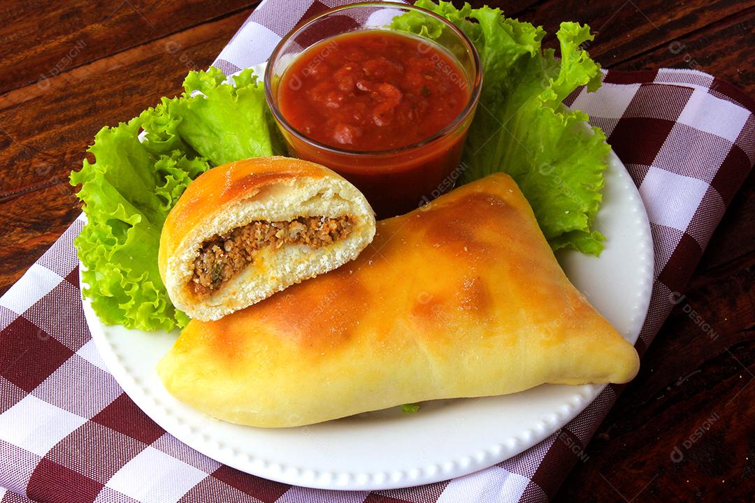 esfiha de carne (sfiha, sfeeha) de origem árabe tradicionalmente adaptada para a culinária brasileira no prato na mesa