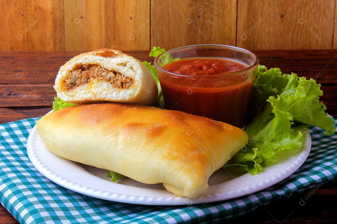 esfiha de carne (sfiha, sfeeha) de origem árabe tradicionalmente adaptada para a culinária brasileira no prato na mesa