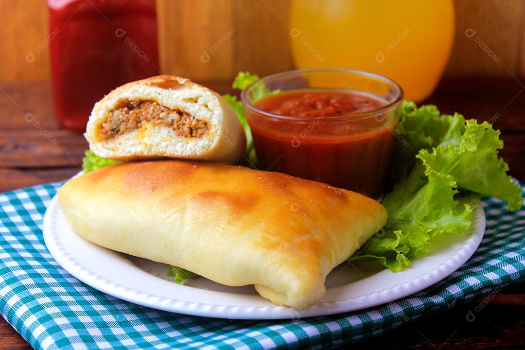 esfiha de carne (sfiha, sfeeha) de origem árabe tradicionalmente adaptada para a culinária brasileira no prato na mesa