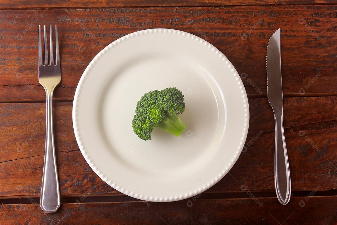 Conceito de restrição calórica. Dieta rigorosa. Vagem fatiada isolada na chapa branca com garfo e faca na mesa de madeira