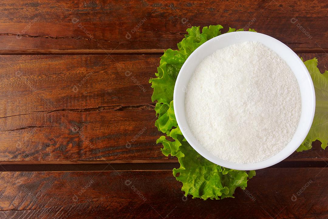 pó de colágeno em tigela de cerâmica sobre folha verde na mesa de madeira rústica. Vista do topo