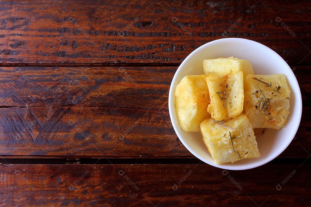 mandioca cozida e frita (mandioca) em tigela de cerâmica na mesa de madeira rústica no restaurante