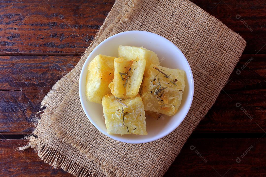 mandioca cozida e frita (mandioca) em tigela de cerâmica na mesa de madeira rústica no restaurante