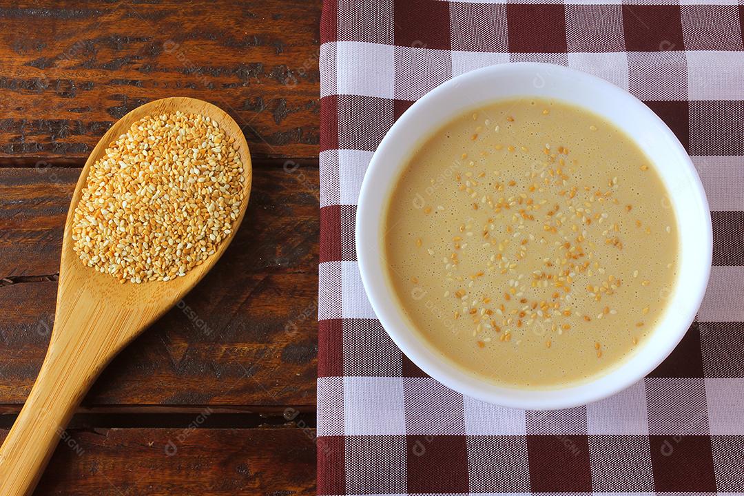Tahine em tigela de cerâmica na mesa de madeira rústica - creme ou pasta feita de sementes de gergelim