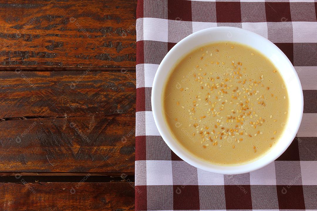 Tahine em tigela de cerâmica na mesa de madeira rústica - creme ou pasta feita de sementes de gergelim