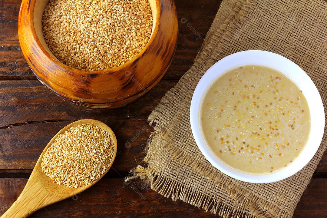 Tahine em tigela de cerâmica na mesa de madeira rústica - creme ou pasta feita de sementes de gergelim