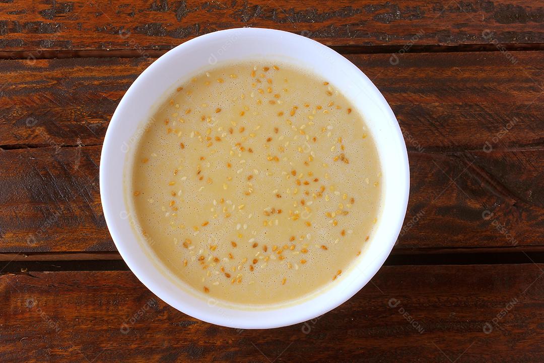 Tahine em tigela de cerâmica na mesa de madeira rústica - creme ou pasta feita de sementes de gergelim