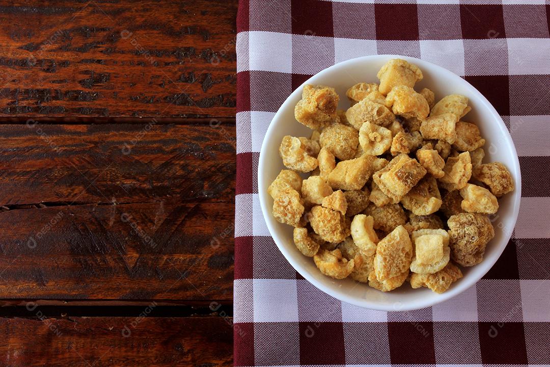 torresmo (torresmo) frito em tigela de cerâmica na mesa de madeira rústica no restaurante