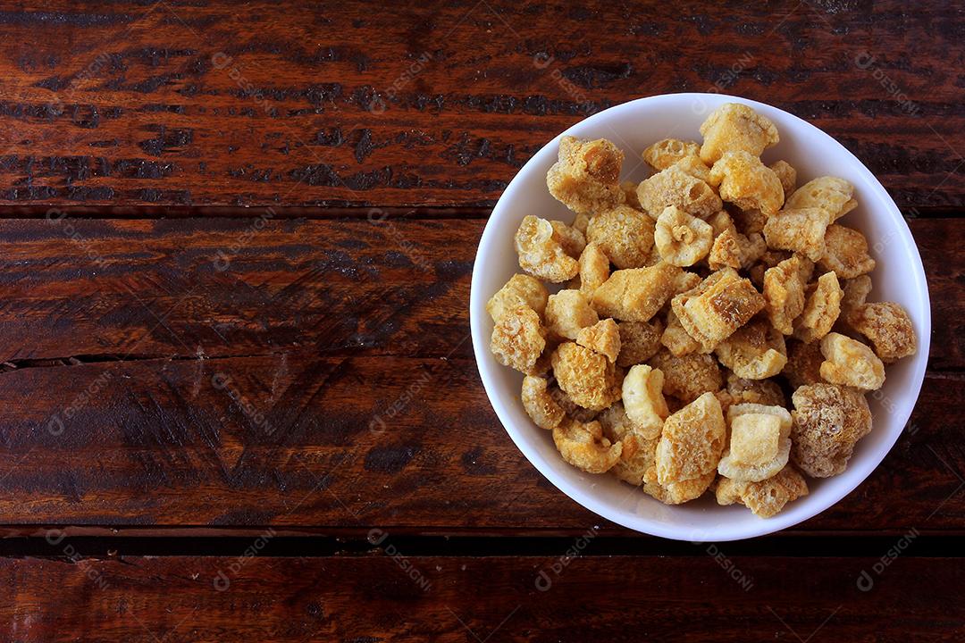 torresmo (torresmo) frito em tigela de cerâmica na mesa de madeira rústica no restaurante