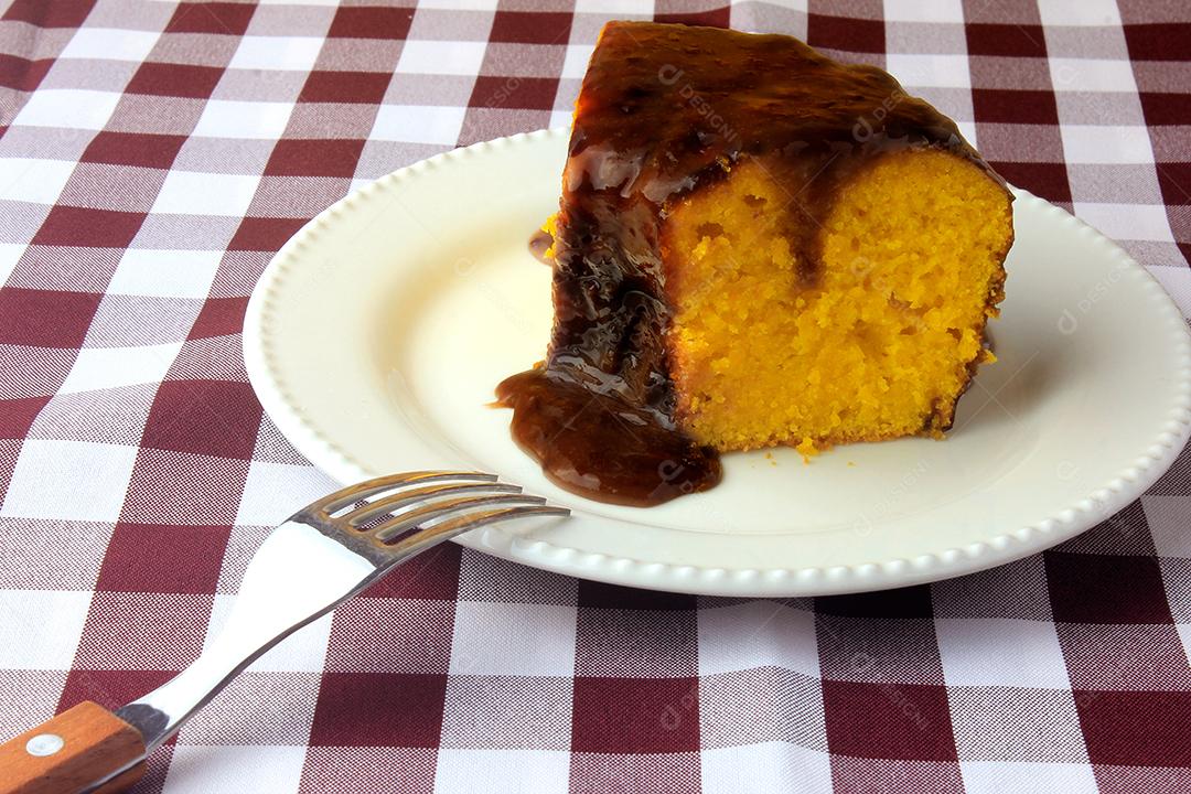 fatia de bolo de cenoura com cobertura de chocolate na placa cerâmica branca na mesa de madeira rústica