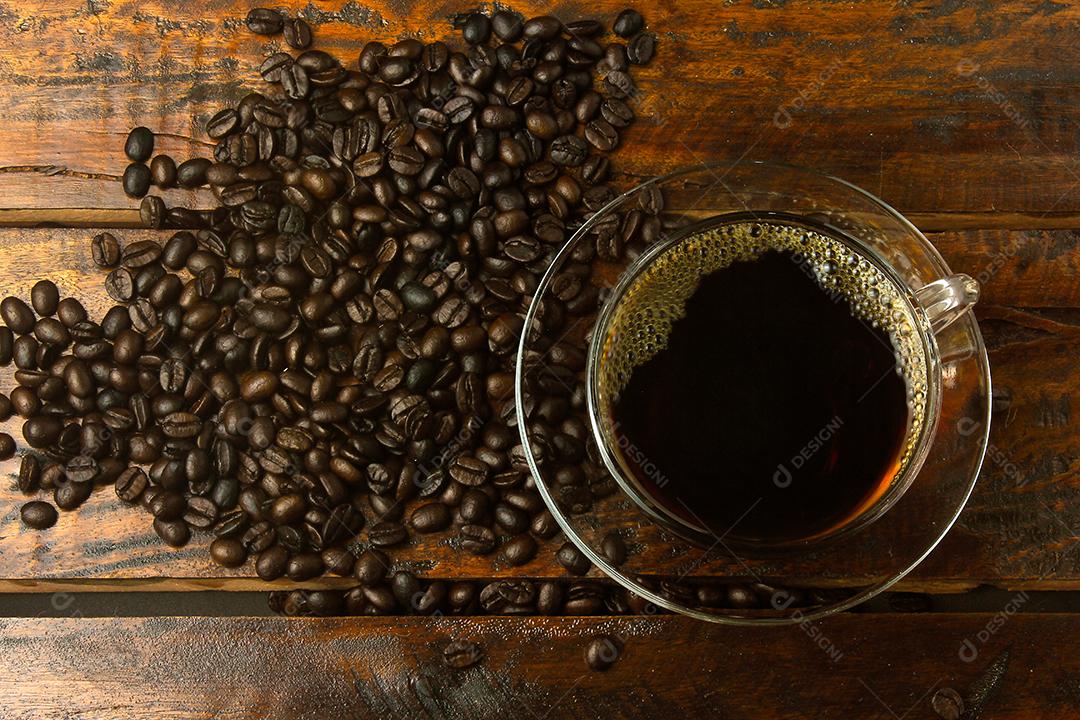 xícara com café fresco e grãos torrados derramados na mesa de madeira rústica. Vista do topo