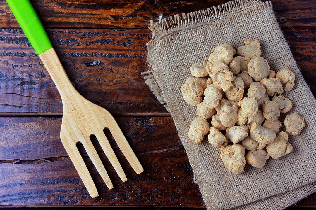 Carne de soja, pedaços em toalha de tecido rústico. Vista superior de pedaços de soja crua em fundo de madeira rústica