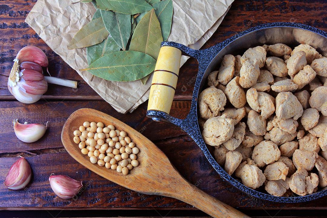 Carne de soja, pedaços em uma panela rústica. Vista superior de pedaços de soja crua em fundo de madeira rústica