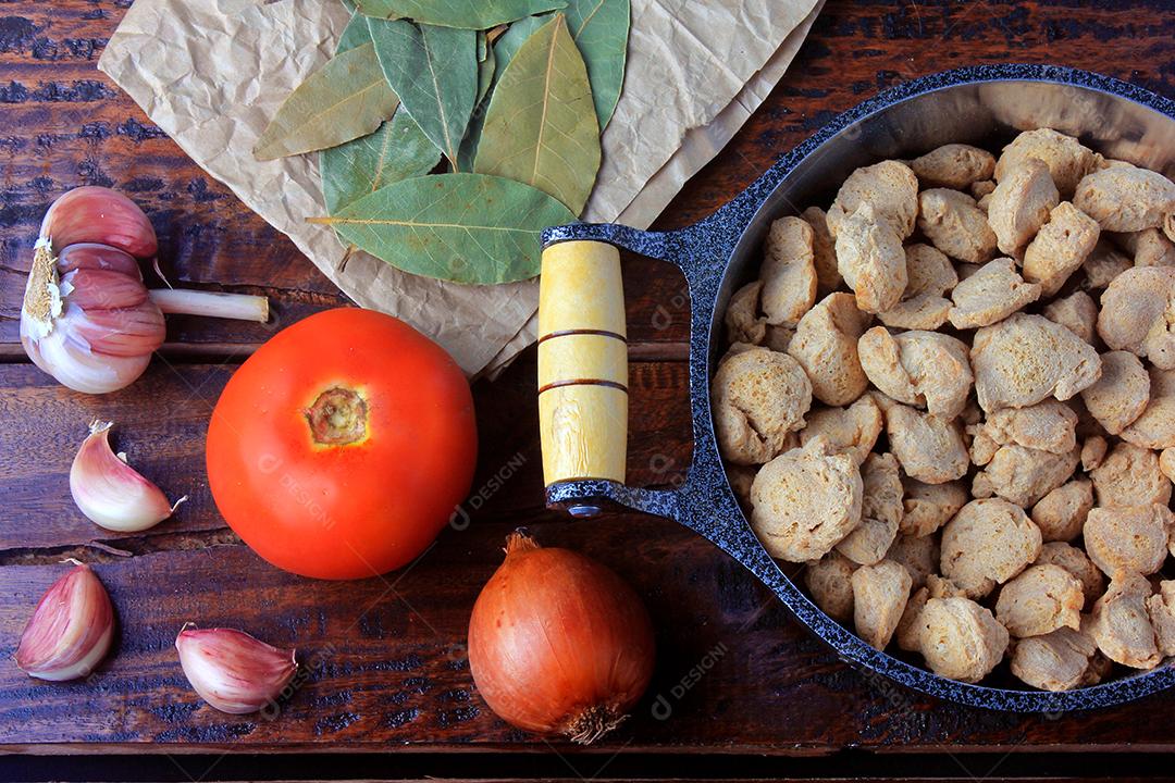 Carne de soja, pedaços em uma panela rústica. Vista superior de pedaços de soja crua em fundo de madeira rústica