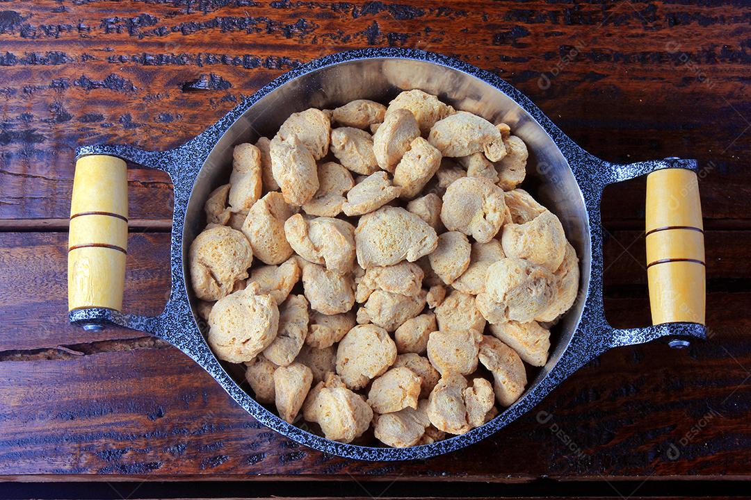 Carne de soja, pedaços em uma panela rústica. Vista superior de pedaços de soja crua em fundo de madeira rústica