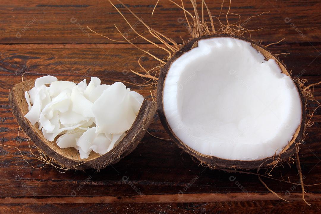 flocos de coco fresco e batatas fritas colocadas em casca e casca isoladas em fundo de madeira rústica