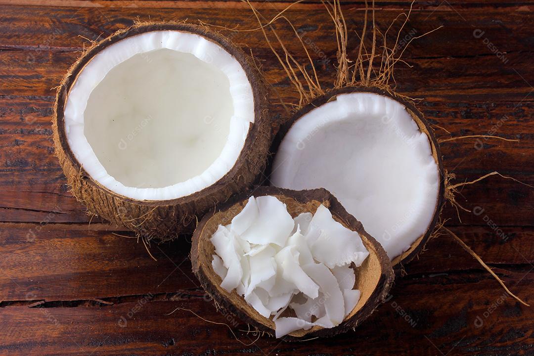 flocos de coco fresco e batatas fritas colocadas em casca e casca isoladas em fundo de madeira rústica