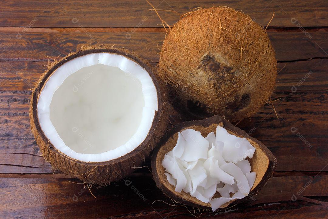 flocos de coco fresco e batatas fritas colocadas em casca e casca isoladas em fundo de madeira rústica