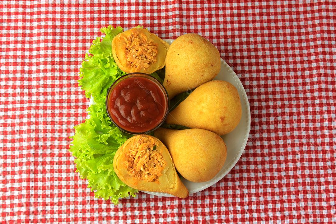 Coxinha no prato, petiscos da cozinha tradicional brasileira recheados com frango, na mesa de madeira rústica