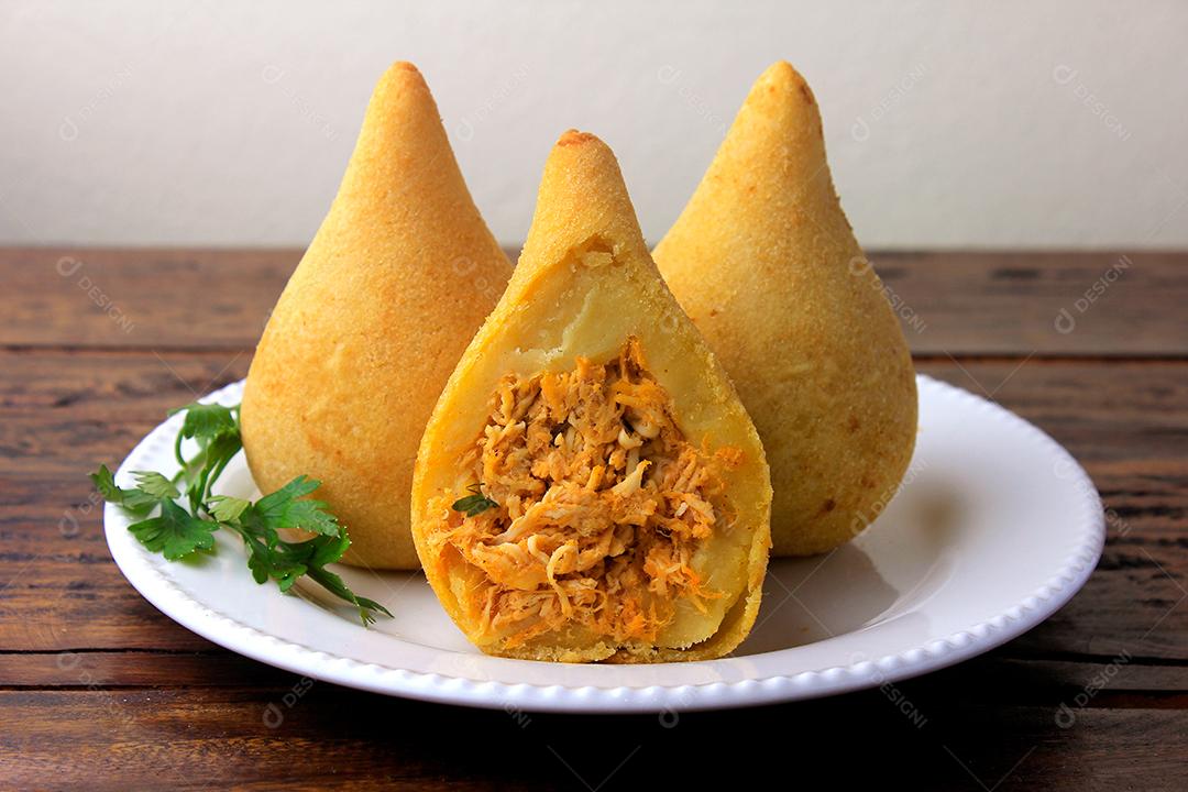 Coxinha no prato, petiscos da cozinha tradicional brasileira recheados com frango, na mesa de madeira rústica