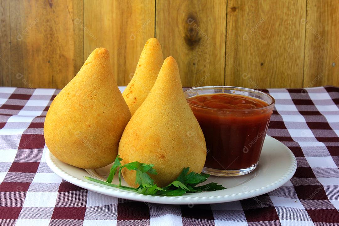 Coxinha no prato, petiscos da cozinha tradicional brasileira recheados com frango, na mesa de madeira rústica