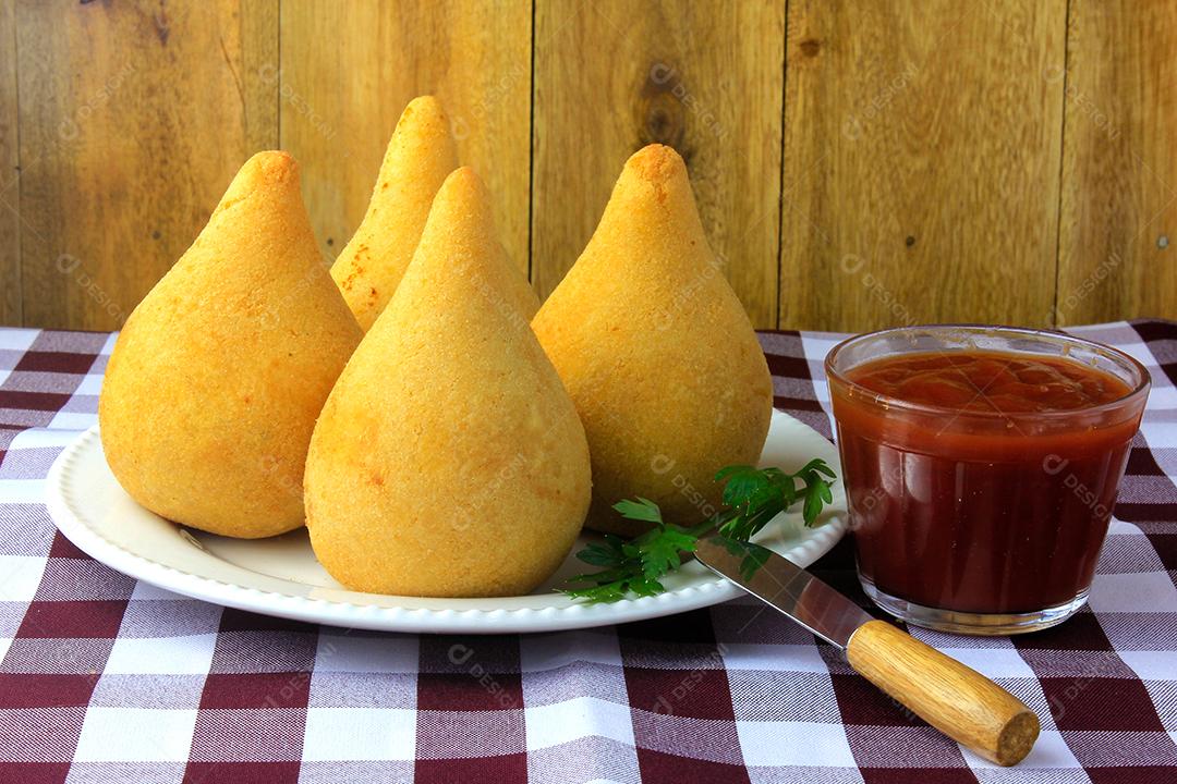 Coxinha no prato, petiscos da cozinha tradicional brasileira recheados com frango, na mesa de madeira rústica