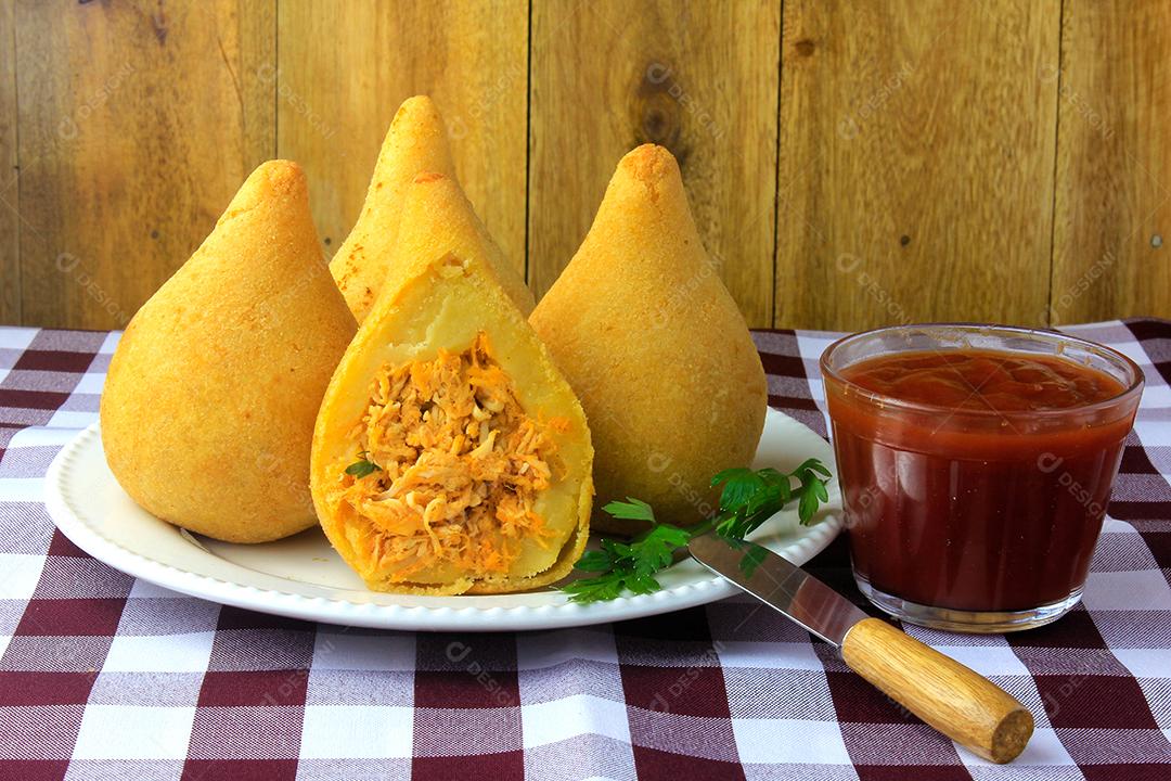 Coxinha no prato, petiscos da cozinha tradicional brasileira recheados com frango, na mesa de madeira rústica