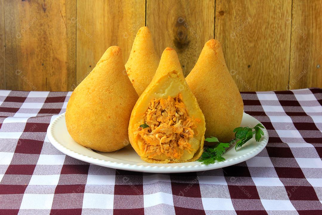 Coxinha no prato, petiscos da cozinha tradicional brasileira recheados com frango, na mesa de madeira rústica