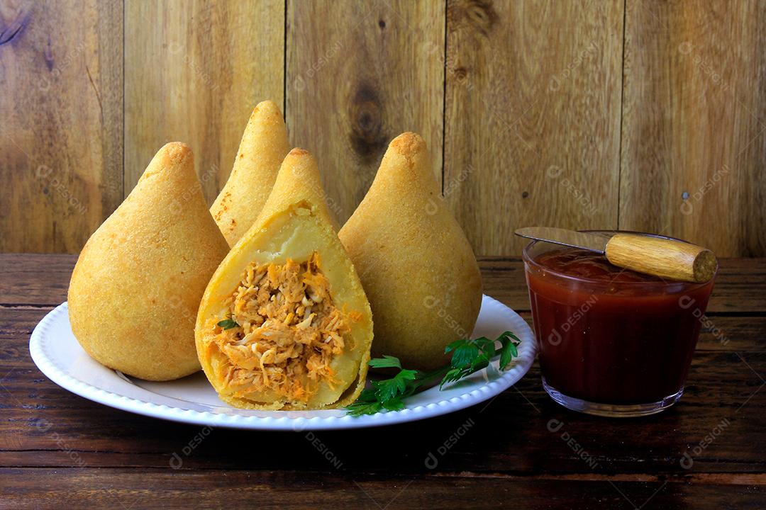 Coxinha no prato, petiscos da cozinha tradicional brasileira recheados com frango, na mesa de madeira rústica