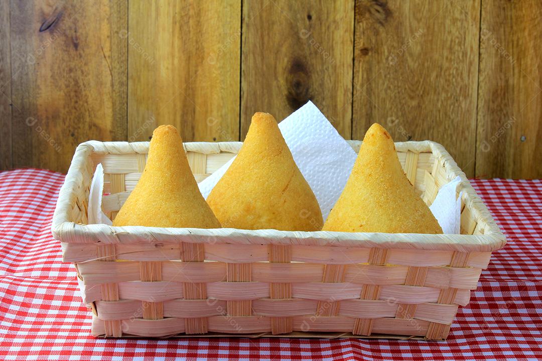 Coxinha no prato, petiscos da cozinha tradicional brasileira recheados com frango, na mesa de madeira rústica