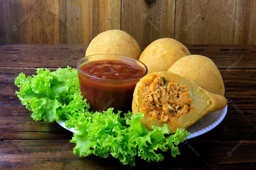 Coxinha no prato, petiscos da cozinha tradicional brasileira recheados com frango, na mesa de madeira rústica
