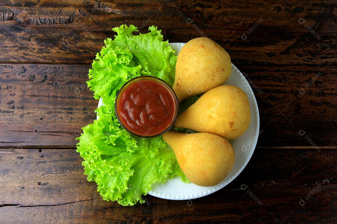 Coxinha no prato, petiscos da cozinha tradicional brasileira recheados com frango, na mesa de madeira rústica